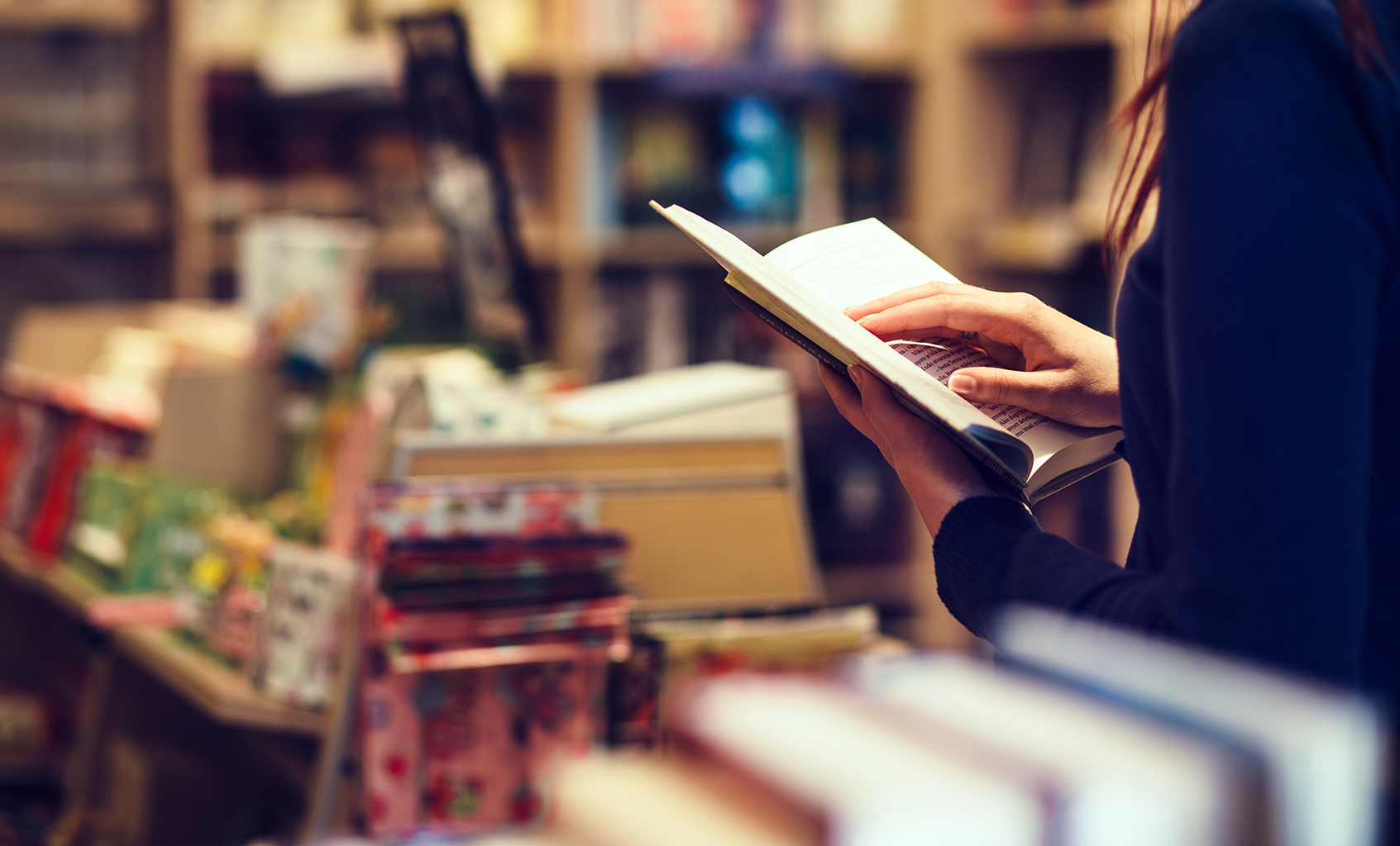 Lady holding an open book inside bookshop